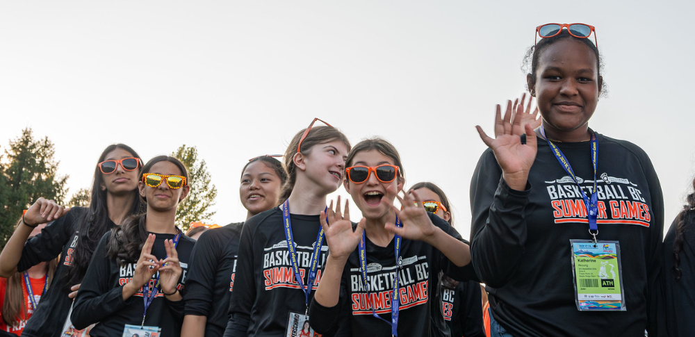 Basketball players wave at the camera while entering the Opening Ceremony